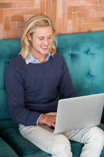Foto glimlachende mens die laptop in restaurant met behulp van