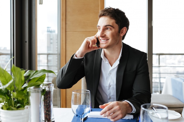 Glimlachende Mens die op telefoon in restaurant spreekt