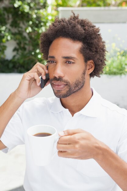 Glimlachende mens op de telefoon die koffie heeft