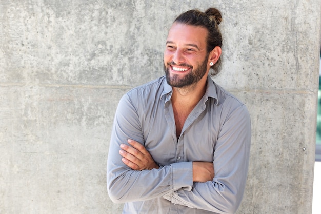 Glimlachende moderne mens met baard die zich met gekruiste wapens bevindt