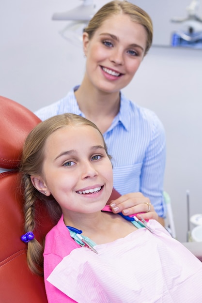 Glimlachende moeder en dochter bij tandkliniek