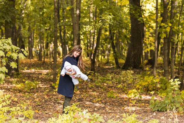 Glimlachende moeder en dochtertje spelen samen in het bos