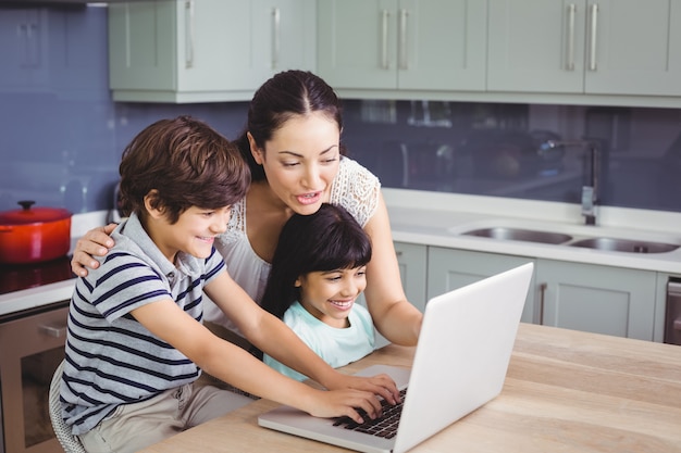 Glimlachende moeder en kinderen die aan laptop werken