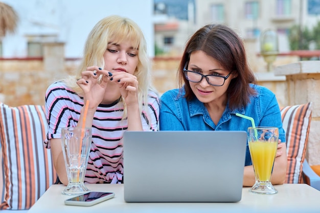 Glimlachende moeder en tienerdochter die samen naar het laptopscherm kijken