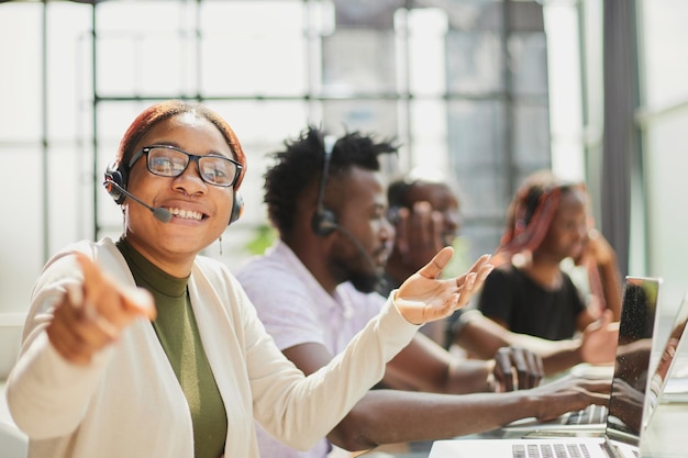 Glimlachende mooie Afrikaanse Amerikaanse vrouw die in call centre met divers team werkt