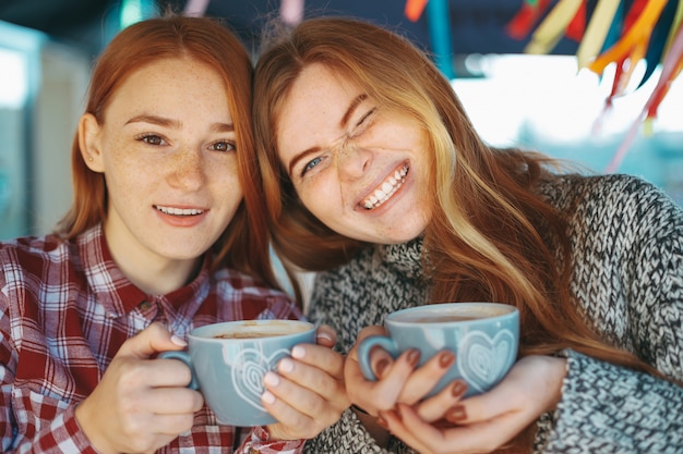 Glimlachende mooie jonge meisjes die met koffie stellen