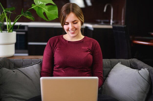 Glimlachende mooie jonge vrouw die computer thuis met behulp van. Hoge kwaliteit foto