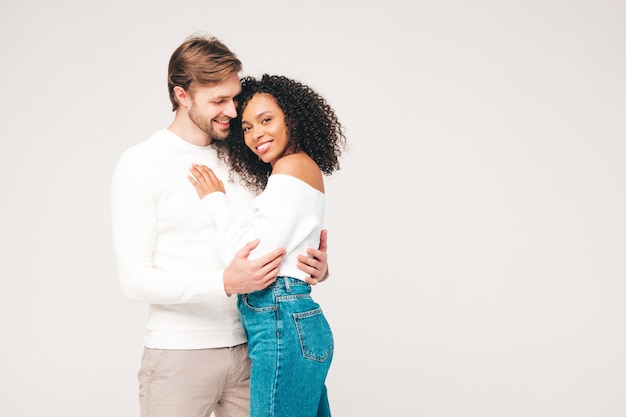 Glimlachende mooie vrouw en haar knappe vriendje. Gelukkige vrolijke multiraciale familie met tedere momenten op grijs