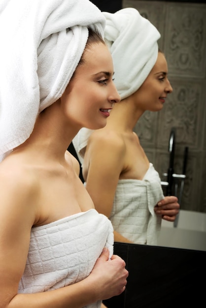 Glimlachende mooie vrouw gewikkeld in een handdoek in de spa