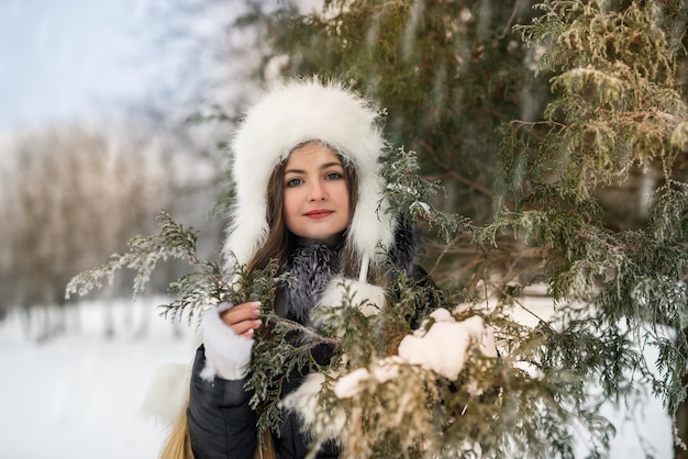 Glimlachende mooie vrouw met boomtakken in winterpark