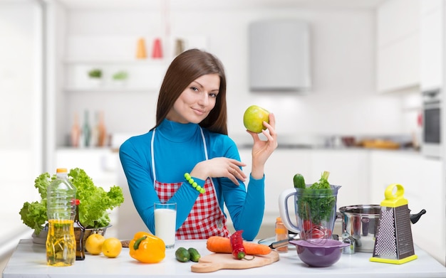 Glimlachende mooie vrouw met groene appel in de keuken