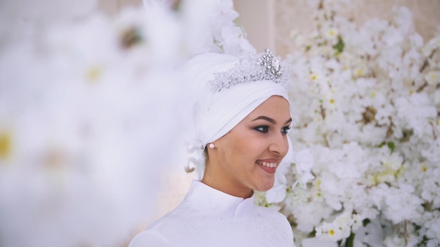 Glimlachende moslimbruid met bruidsmake-up in bloemen