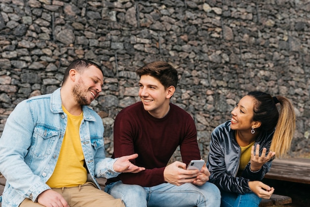 Foto glimlachende multi-etnische vrienden die en telefoon spreken bekijken