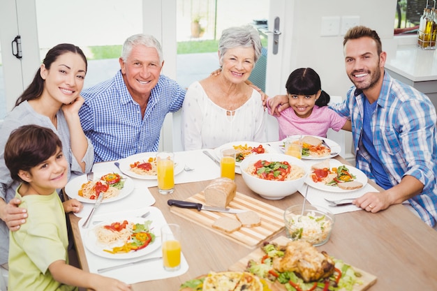 Glimlachende multigeneratiefamilie bij eettafel