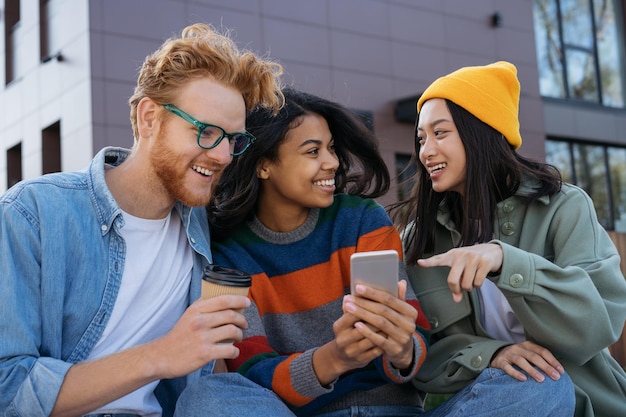 Glimlachende multiraciale vrienden die elkaar op straat ontmoeten via mobiele telefoon