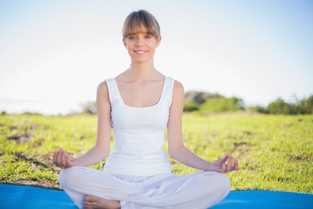 Glimlachende natuurlijke jonge vrouw die yoga doet