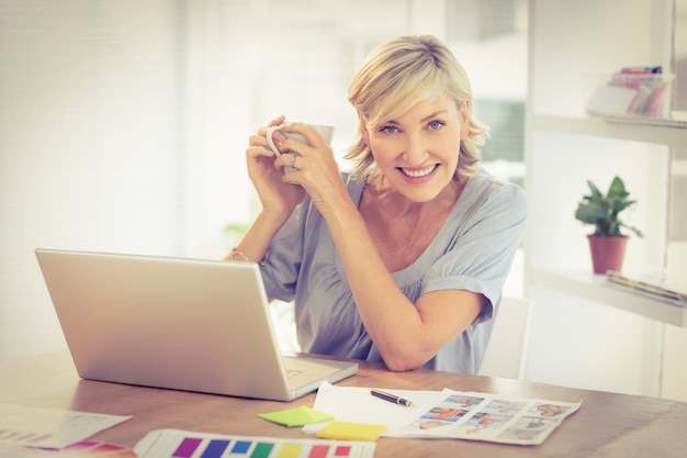 Glimlachende onderneemster die aan laptop werkt