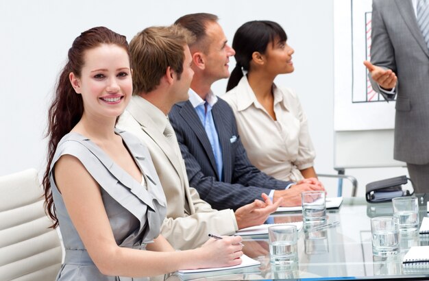 Glimlachende onderneemster die aan zijn collega luistert die een presentatie geeft