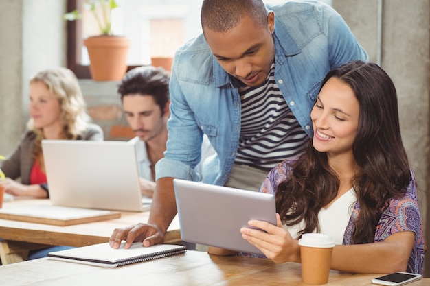 Glimlachende onderneemster die digitale tablet tonen aan mannelijke collega in bureau