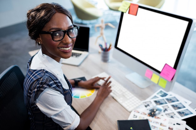 Glimlachende onderneemster die een computer met behulp van