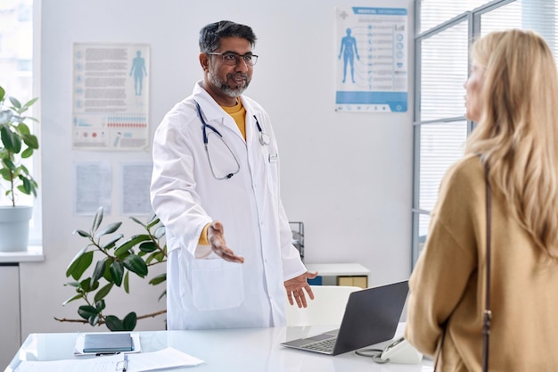 Glimlachende oudere dokter verwelkomt patiënt