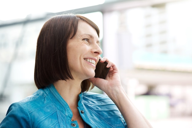 Glimlachende oudere vrouw die mobiele telefoon met behulp van