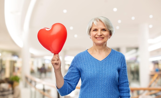 Foto glimlachende oudere vrouw met een rode hartvormige ballon