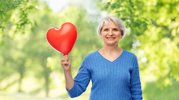 glimlachende oudere vrouw met een rode hartvormige ballon