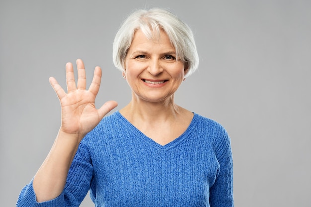 glimlachende oudere vrouw met handpalm of vijf vingers