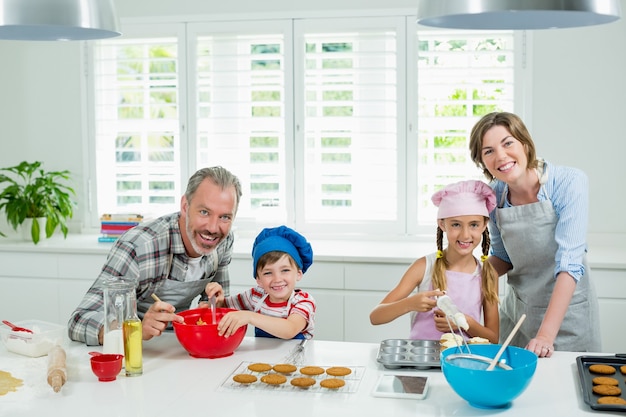 Glimlachende ouders en kinderen die koekjes in keuken voorbereiden