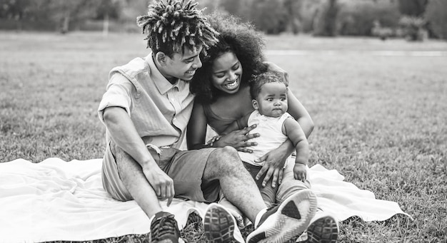 Foto glimlachende ouders kijken naar hun dochter terwijl ze in het park zitten.