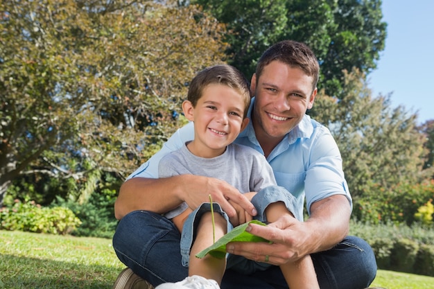 Glimlachende papa en zoon die een blad houden