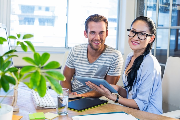 Glimlachende partners die aan tablet samenwerken