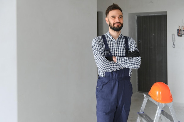 Glimlachende reparateur die zich dichtbij trapladder bevindt en camera bekijkt