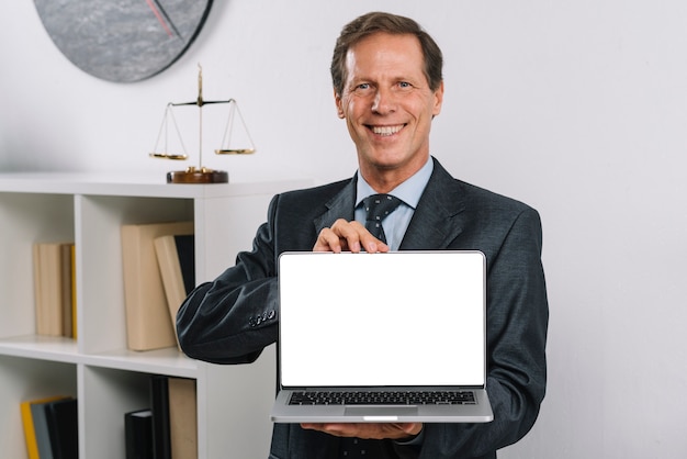 Glimlachende rijpe advocaat die het lege laptop scherm tonen die zich in de rechtszaal bevinden