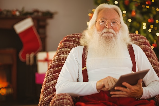 Glimlachende santa die digitale tablet gebruikt