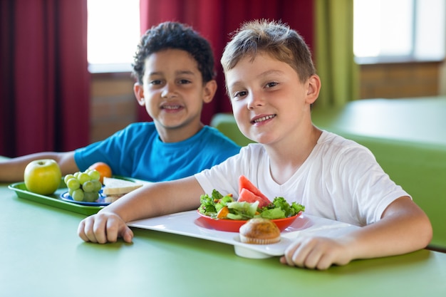 Glimlachende schooljongens die maaltijd hebben