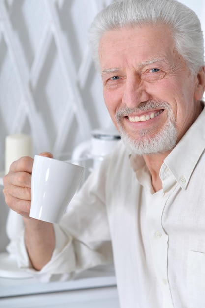 Glimlachende senior man die thuis thee drinkt
