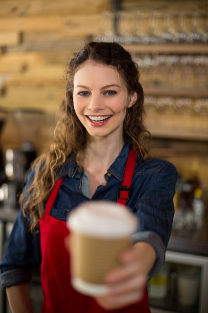 Glimlachende serveerster die een kop van koffie in koffie dient