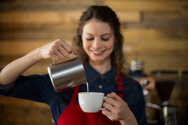 Glimlachende serveerster die kop van koffie maakt