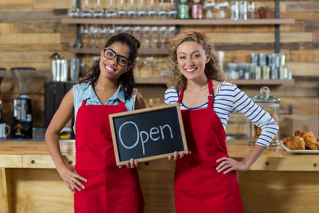 Glimlachende serveerster twee die zich met open uithangbord in koffie bevinden