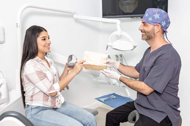 Glimlachende Spaanse mannelijke tandarts die voorschrift geeft aan vrouwelijke patiënt