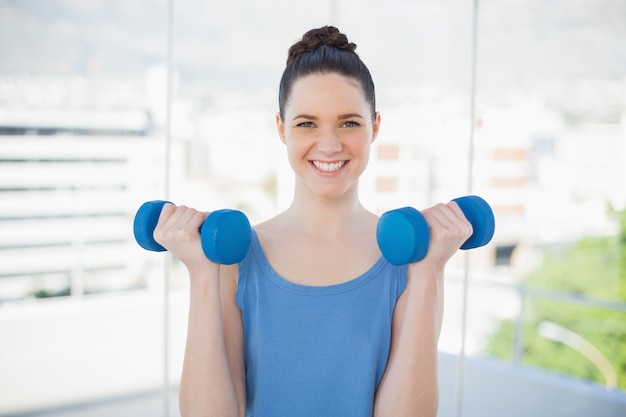 Glimlachende sportieve vrouw die met domoren uitoefent