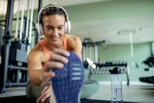 Foto glimlachende sportvrouw die haar been strekt tijdens het trainen in een sportschool