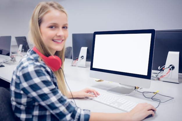 Glimlachende student die aan computer bij universiteit werkt