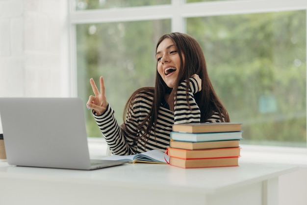 Glimlachende studente studeert online met laptop gelukkige jonge vrouw leert taal luister lezing bekijk webinar schrijf notities kijk naar laptop zit in thuisonderwijs op afstand