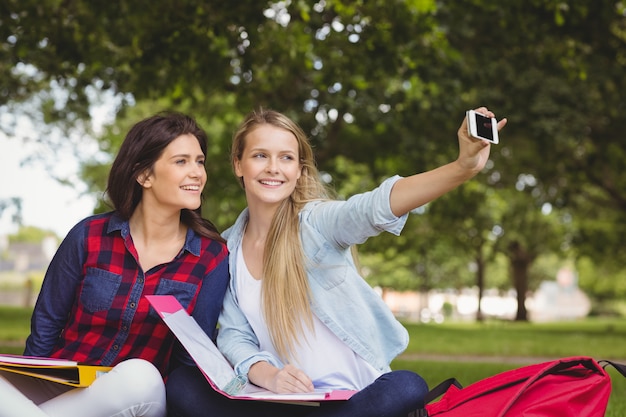 Glimlachende studenten die een selfie openlucht nemen bij park