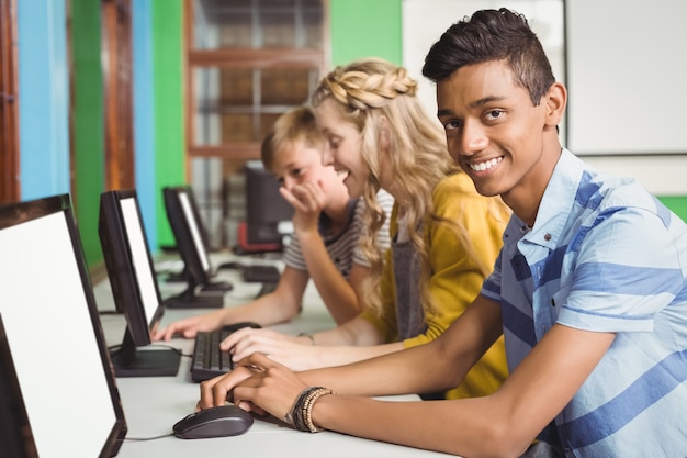 Glimlachende studenten die in computerlokaal studeren