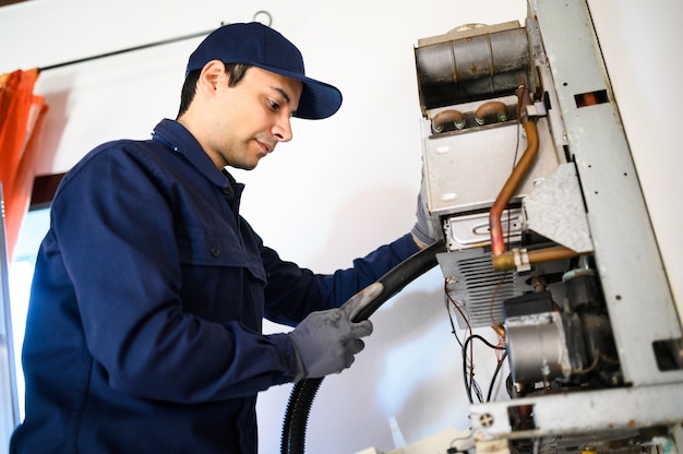 Foto glimlachende technicus die een warmwaterboiler repareert