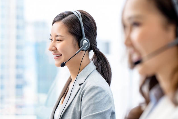 Glimlachende telemarketing Aziatische vrouw die in call centrebureau werken